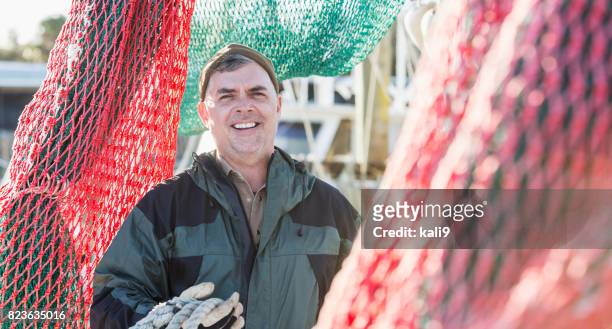volwassen man op commerciële vissersboot omringd door netten - shrimp boat stockfoto's en -beelden