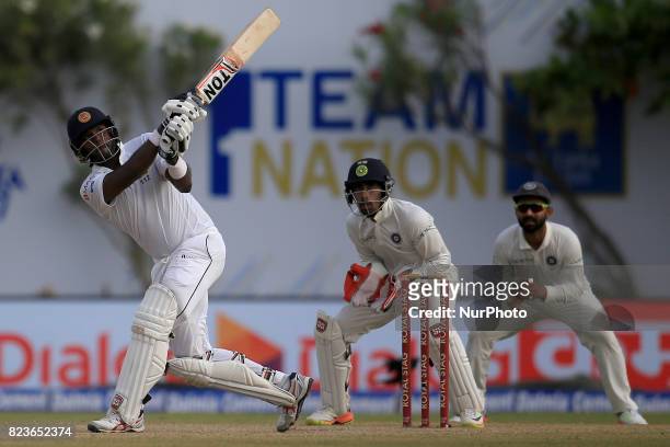 Sri Lankan cricketer Angelo Mathews plays a shot as Indian Wicket keeper Wriddhiman Saha looks on during the 2nd Day's play in the 1st Test match...