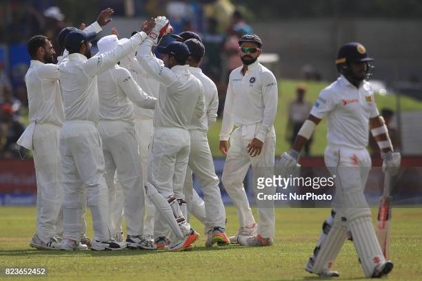 Indian cricket captain Virat Kohli celebrates with his team mates as Sri Lanka's Kusal Mendis walks back to the pavilion after being dismissed during...
