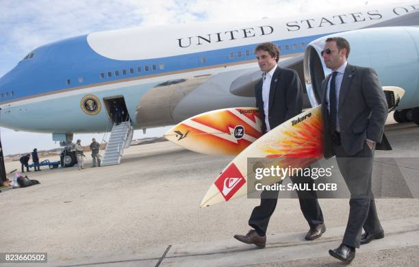 White House staffers Ben Finkenbinder and Nick Shapiro carry surfboards as they walk away from Air Force One after arriving with US President Barack...