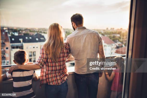 rear view of family standing on a penthouse terrace and looking at the view. - penthouse girl stock pictures, royalty-free photos & images