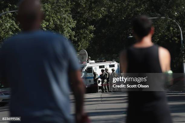 Residents watch as Chicago Police SWAT team members surround a house in the Humboldt Park neighborhood where they believe a man responsible for a...