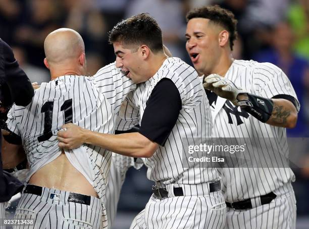 Brett Gardner of the New York Yankees is mobbed by teammates Tyler Wade and Gary Sanchez after Gardner hit a walk off home run in the 11th inning to...