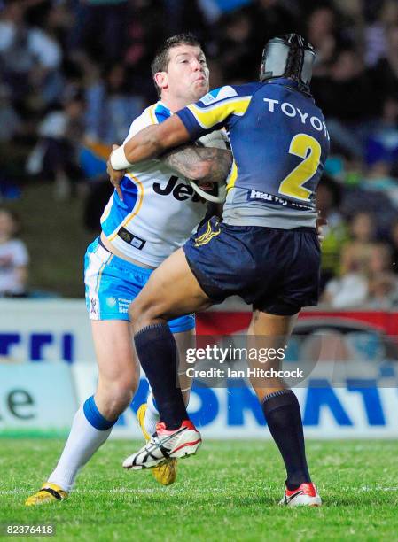 Brett Delaney of the Titans is tackled by Ty Williams of the Cowboys during the round 23 NRL match between the North Queensland Cowboys and the Gold...