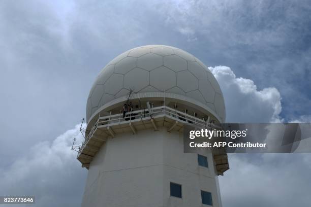 Workers fasten antennas outside a radar at the Sandiao Cape in New Taipei City, northeast of Taiwan on July 28 as typhoon Senat approaches. / AFP...