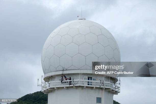 Workers fasten antennas outside a radar at the Sandiao Cape in New Taipei City, northeast of Taiwan on July 28 as typhoon Senat approaches. / AFP...