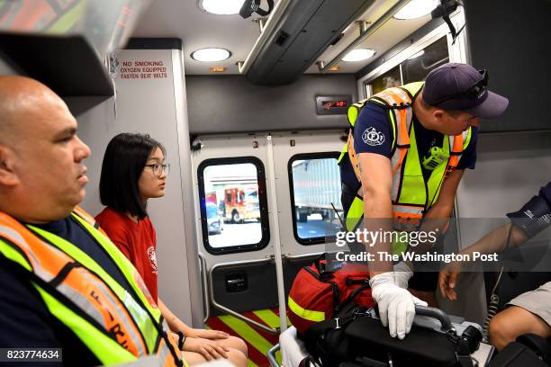 Hannah Kim a rising sophomore at Poolesville High School watches in the back of an ambulance as master firefighter/paramedic Argie Koepke, left, and...