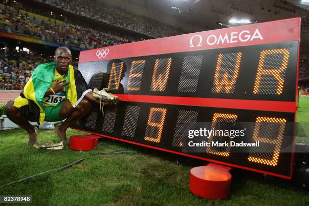 Usain Bolt of Jamaica poses by the clock displaying his winning time after the Men's 100m Final at the National Stadium on Day 8 of the Beijing 2008...