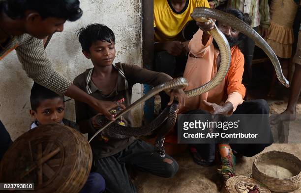 In this photo taken on July 25 the children of Indian snake charmers hold a cobra snake in Kapari village, around 40km southwest of Allahabad in...
