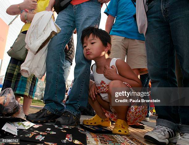 Chinese girl looks at a pin collection belonging to Dan Baker, an American tourist from Hot Springs, Arkansas August 16, 2008 in Beijing, China....