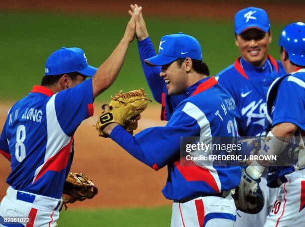 South Korea's Jeong Kuenwoo high-fives relief pitcher Chong Taehyon after he closed out the game against Japan and clinched victory in the bottom of...