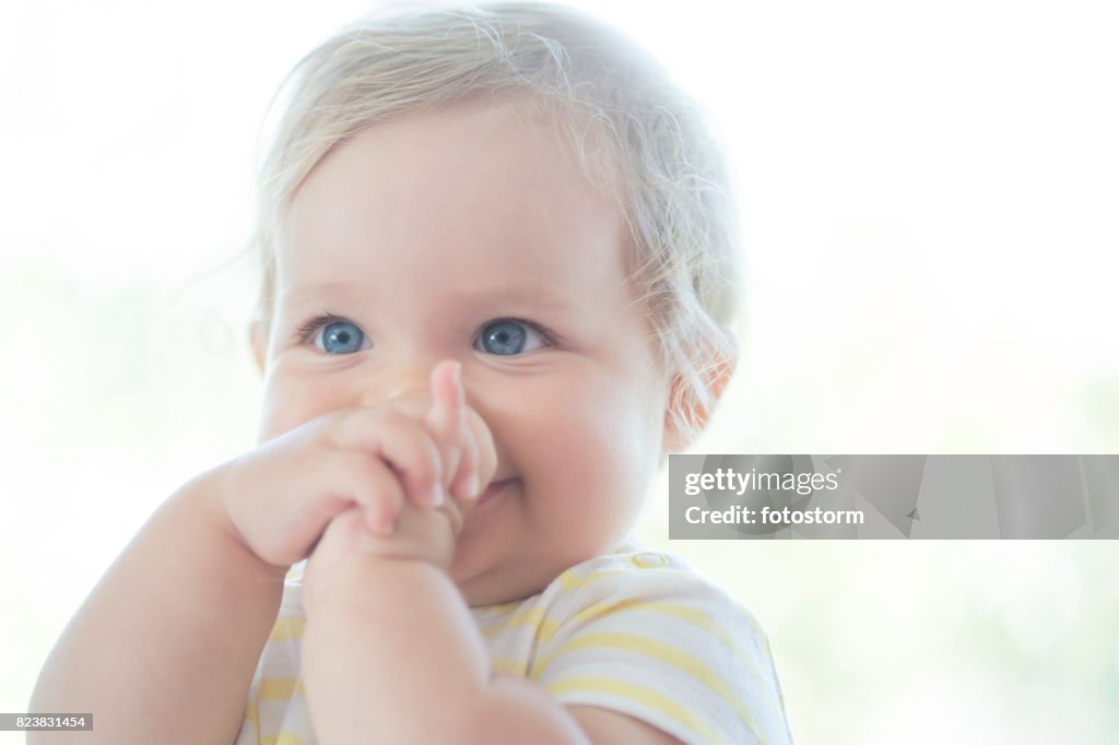 Cute baby with her fingers in her mouth