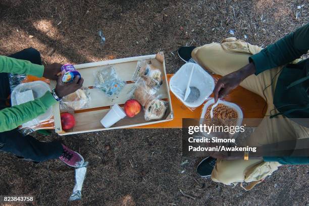 Father and son asylum seeker eat lunch provided by staff, the Hub CARA centre feed nearly 1000 asylum seekers per day on July 27, 2017 in Bologna,...