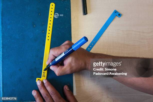 Member of staff writes the code number assigned to an asylum seeker on a wrist band This is to check the presences of the asylum seeker every day...