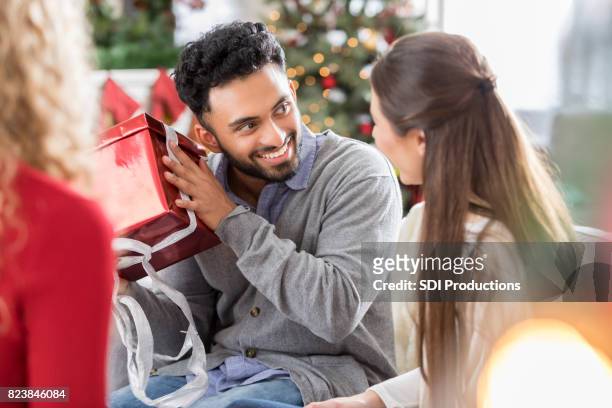 mannen skakar julklapp som under firande med vänner - shaking bildbanksfoton och bilder