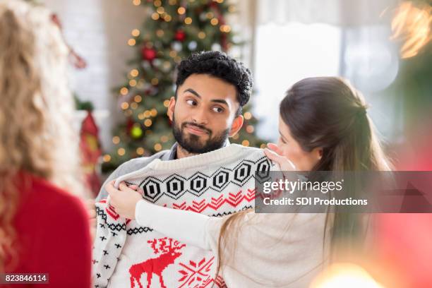 young man is disappointed with new christmas sweater - bad gift stock pictures, royalty-free photos & images