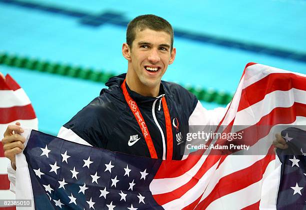 Michael Phelps of the United States smiles with the American flag as he wears his eighth gold medal after the Men's 4x100 Medley Relay at the...