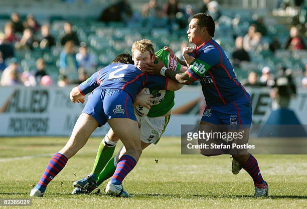 Joel Monaghan of the Raiders is tackled during the round 23 NRL match between the Canberra Raiders and the Newcastle Knights at Canberra Stadium on...