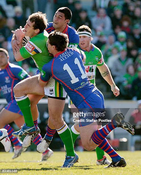 Terry Campese of the Raiders is tackled during the round 23 NRL match between the Canberra Raiders and the Newcastle Knights at Canberra Stadium on...