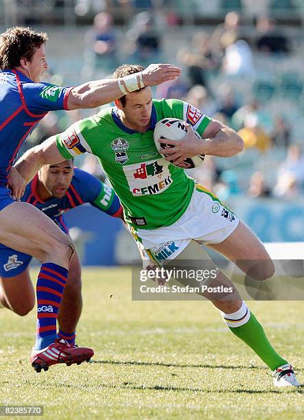 Colin Best of the Raiders is tackled during the round 23 NRL match between the Canberra Raiders and the Newcastle Knights at Canberra Stadium on...