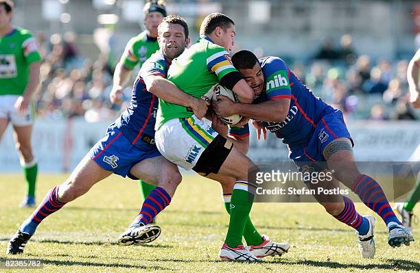 Trevor Thurling of the Raiders is tackled during the round 23 NRL match between the Canberra Raiders and the Newcastle Knights at Canberra Stadium on...
