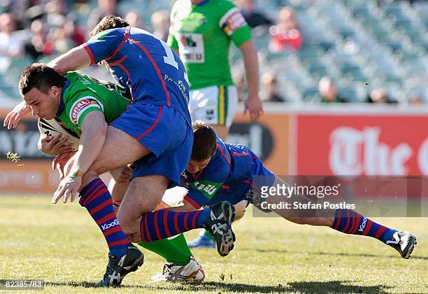 Justin Carney of the Raiders is tackled during the round 23 NRL match between the Canberra Raiders and the Newcastle Knights at Canberra Stadium on...