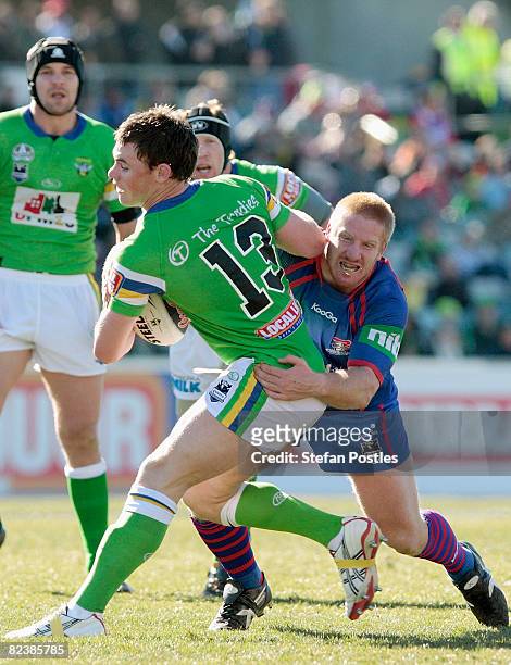Joe Picker of the Raiders is tackled during the round 23 NRL match between the Canberra Raiders and the Newcastle Knights at Canberra Stadium on...