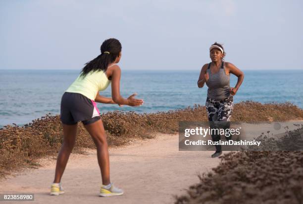 a woman runs with coach support. - team encouragement stock pictures, royalty-free photos & images