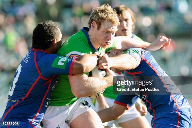 Joel Monaghan of the Raiders is tackled during the round 23 NRL match between the Canberra Raiders and the Newcastle Knights at Canberra Stadium on...