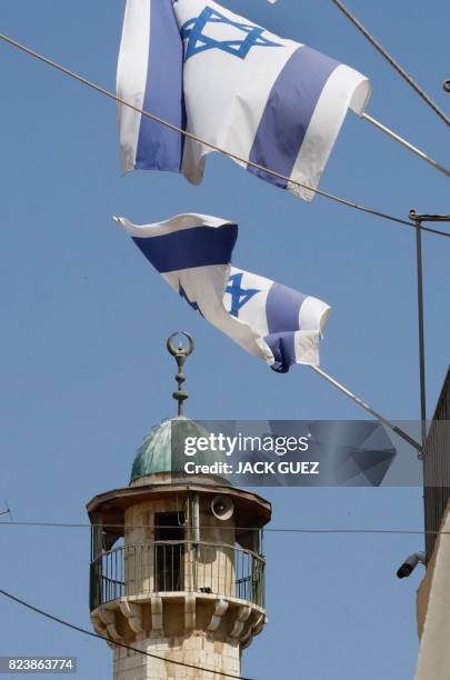 Israeli flags flutter near the minaret of a mosque in Jerusalem's old city on July 28, 2017. - Palestinians held mass prayers outside of a sensitive...