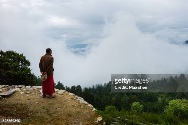 a bhutanese lama is watching the mountain range covered by fog - disparo bildbanksfoton och bilder