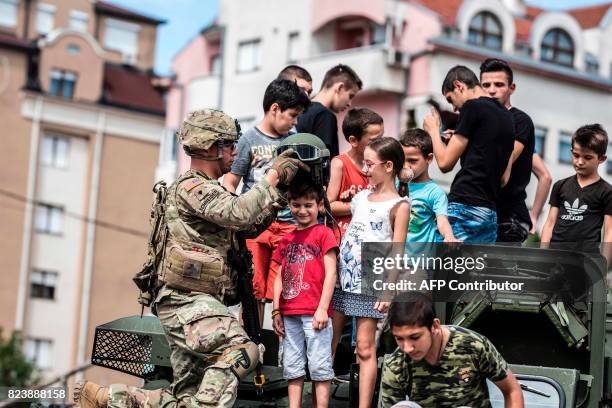 Soldier puts a helmet on a child as they stand on a US army vehicle during a presentation of US vehicles and weapons in Kumanovo on July 28, 2017....