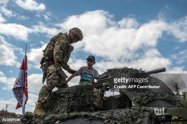 Soldier shows his vehicle to a Macedonian child during a presentation of US vehicles and weapons in Kumanovo on July 28, 2017. Some 300 US soldiers,...