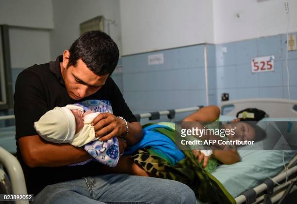 Venezuelan national Jose Luis Gonzales, holds his newborn as his wife Brecia Triago, rests at the Erasmo Meoz University Hospital in Cucuta, North of...