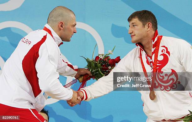 Szymon Kolecki of Poland, silver, Arsen Kasabiev of Georgia, bronze, receive their medals after winning the men's 94kg weightlifting event held at...