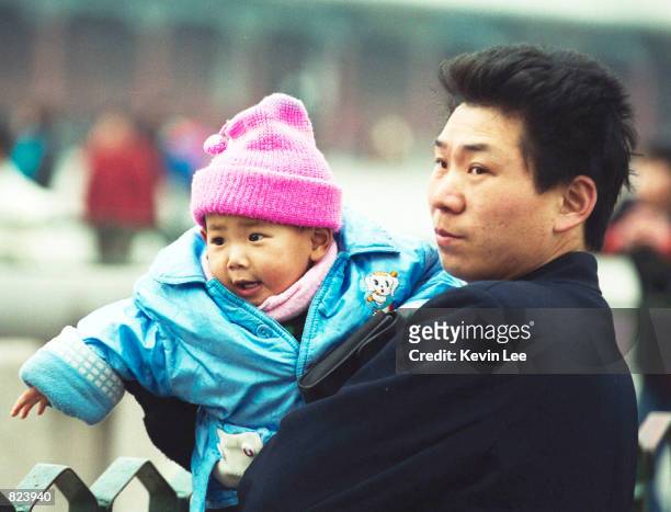 Chinese man holds his son as they visit the Forbidden city in Beijing, China, February 20, 2001. A new Chinese law permits couples to have only one...