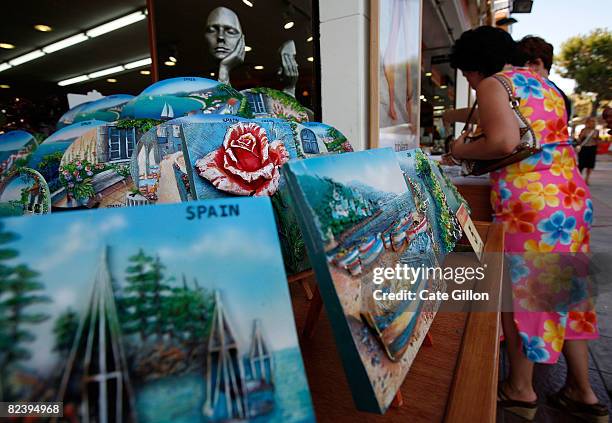 Tourists look at items at a souvenir shop on August 17, 2008 in Santa Susanna, Spain. Feeling the pinch from the credit crunch many British tourists...