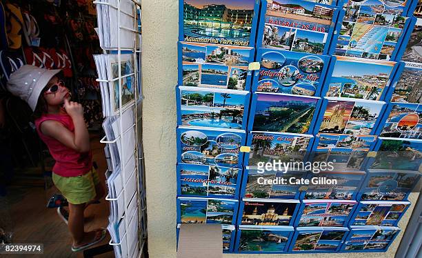 Young tourist considers postcards in a souvenir store on August 17, 2008 in Malgrat de Mar, Spain. Feeling the pinch from the credit crunch many...
