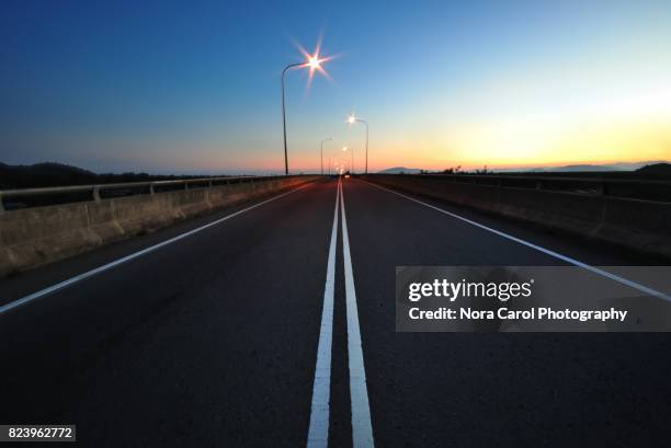 empty asphalt road with lamp post during sunrise - street light post stock pictures, royalty-free photos & images