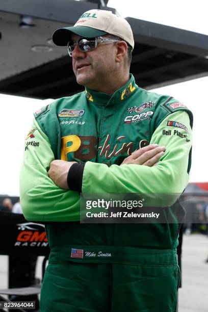 Mike Senica, driver of the Chevrolet, stands in the garage area during practice for the NASCAR Camping World Truck Series Overton's 150 at Pocono...