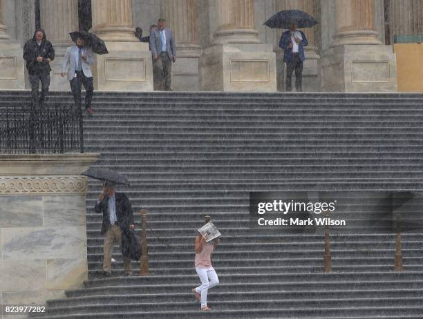 As heavy rain falls, House Republican Conference Vice Chairman Rep. Lynn Jenkins holds a paper over her head as she and other members walk down the...