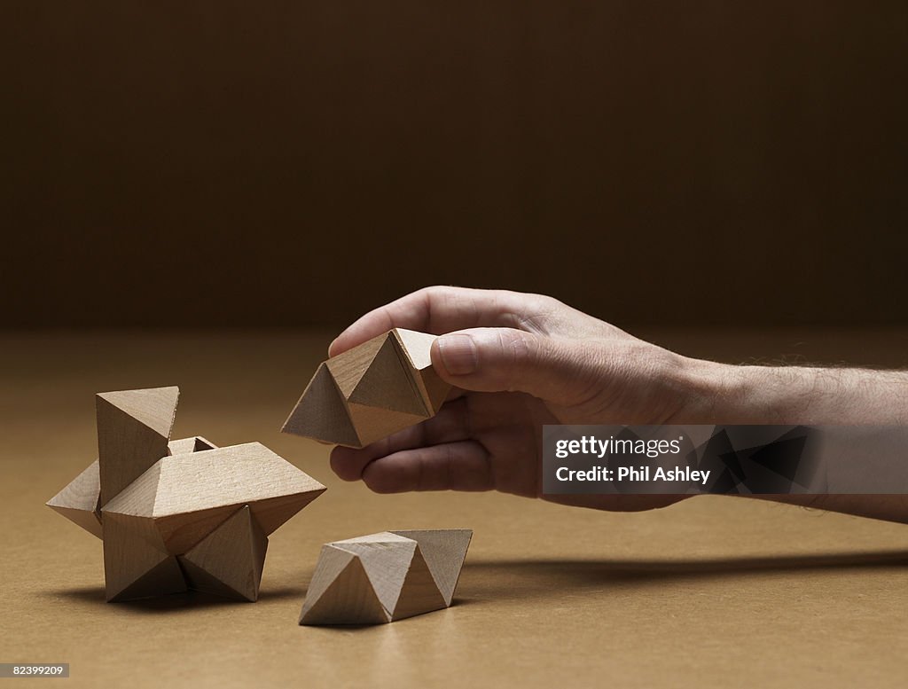 Old man solving a wooden puzzle
