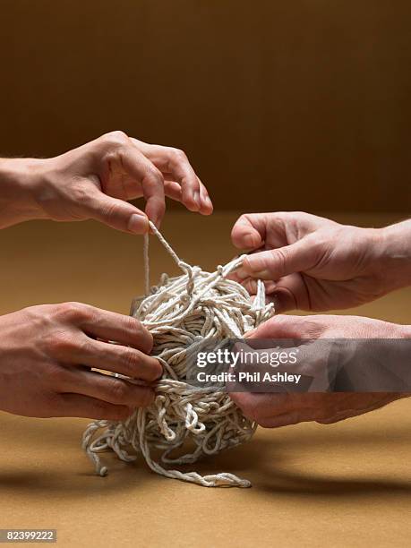 two men trying to untangle a giant knot - untangle stockfoto's en -beelden