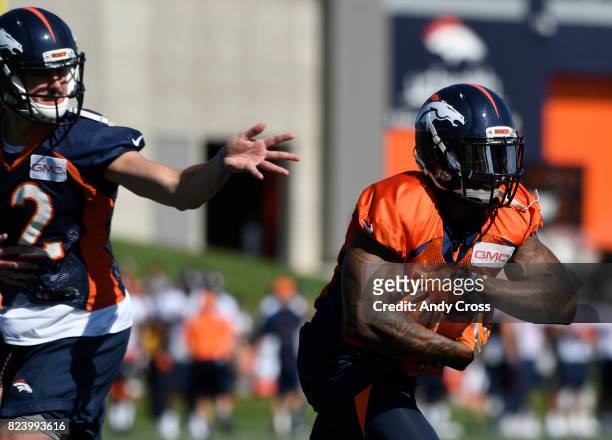 Denver Broncos quarterback Paxton Lynch hands off to RB Steven Ridley, #4, at Dove Valley July 28, 2017.