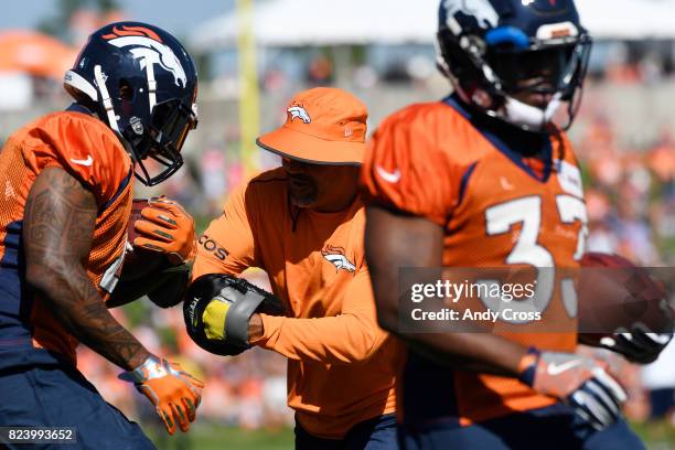 Denver Broncos RB coach Eric Studesville, center, tries to punch to ball away from RB Steven Ridley, left, at Dove Valley July 28, 2017. Denver...