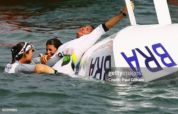 Isabel Swan and Fernanda Oliveira of Brazil celebrate with team official after finishing third overall following the Women's 470 class medal race...