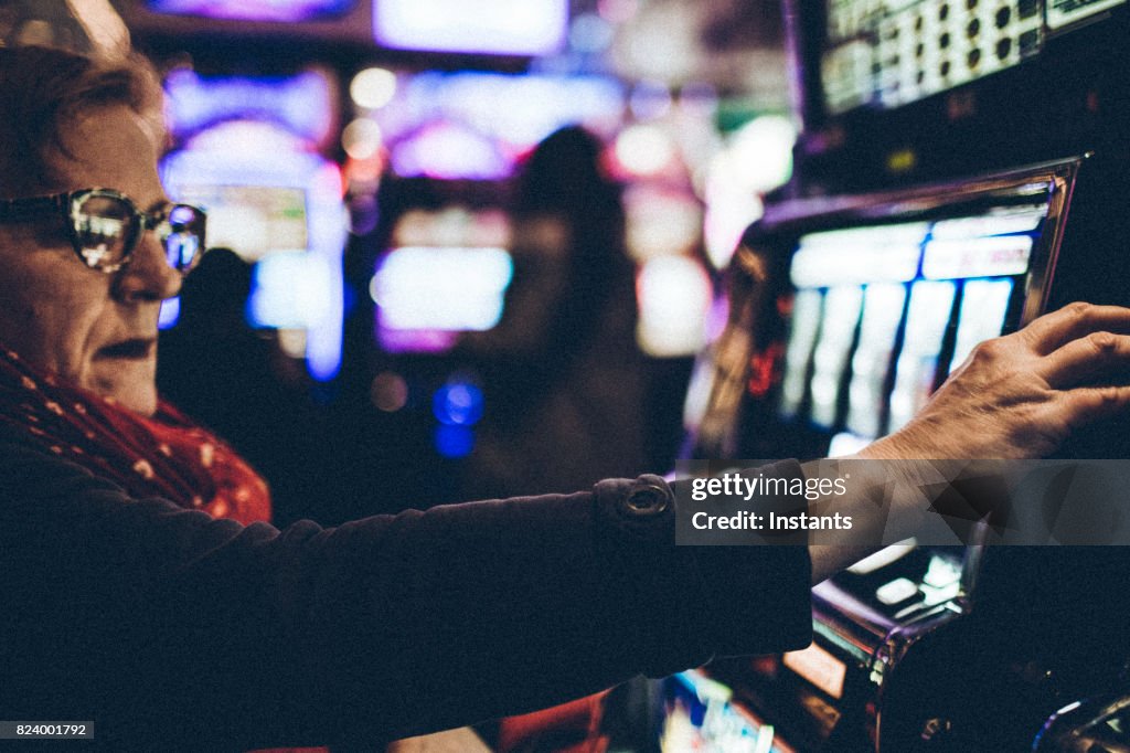 Gambling 59 year old woman playing a slot machine in one of Las Vegas casinos.