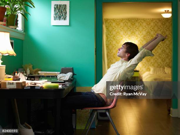 young man streching at desk - preguiça conceito imagens e fotografias de stock