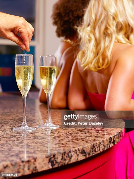 spiking girls champagne drinks in bar. - violenza sessuale foto e immagini stock