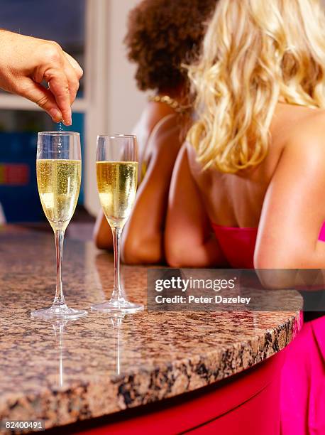 spiking girls champagne drinks in bar. - drugsmisbruik stockfoto's en -beelden